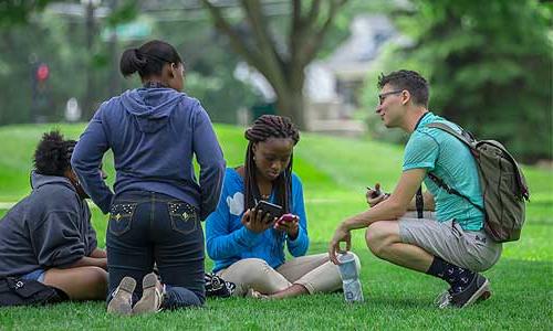 a group of students sitting on a lawn.